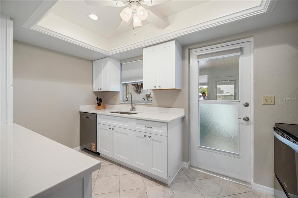 A kitchen with white cabinets, quartz countertops, a stainless steel dishwasher, and a glass-paneled door — 702 FAIR WINDS DRIVE UNIT 702, NOKOMIS, FL