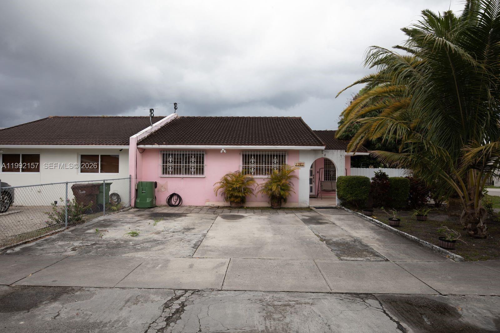 A pink single-story house with a concrete driveway and a large palm tree in front — 1261 W 43rd Pl, Hialeah FL 33012, HIALEAH, FL