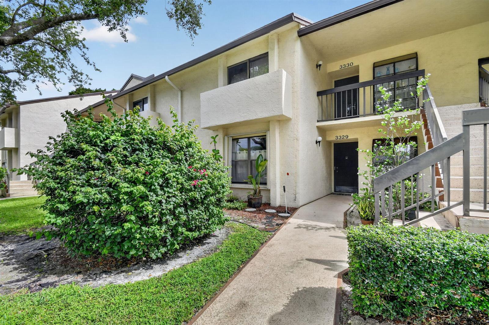 A two-story apartment building exterior with a concrete walkway leading to two entrance doors — 3329 Perimeter Drive, FL 33467, FL