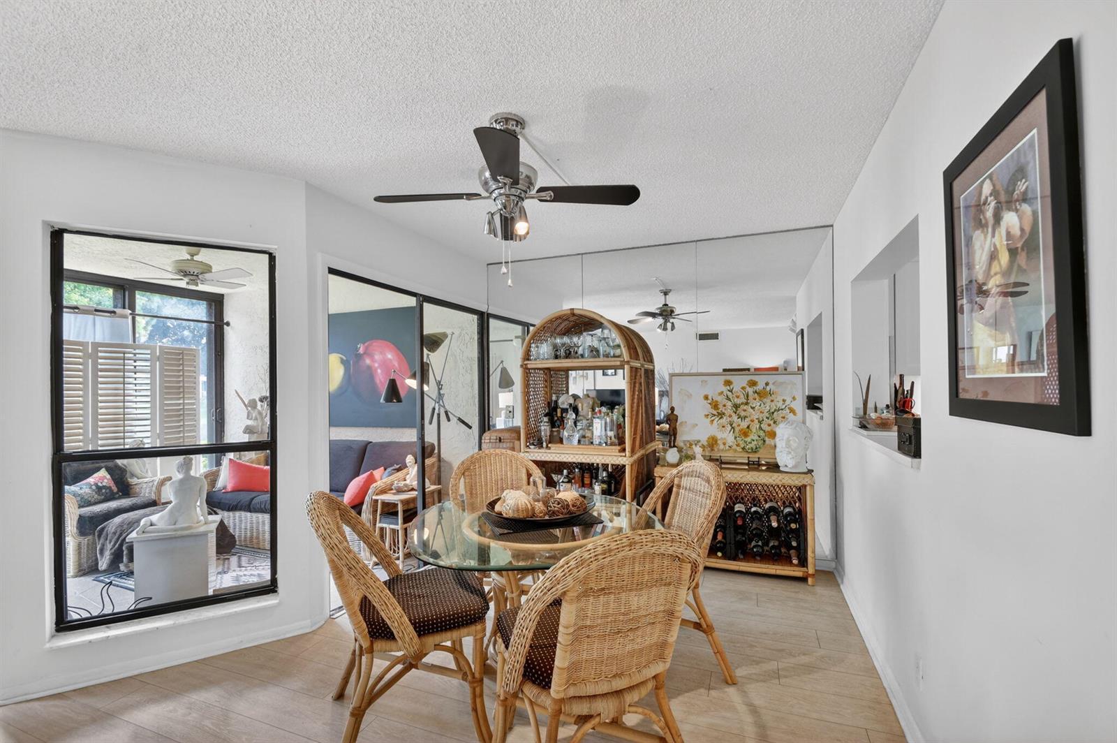 A dining area with a glass-topped wicker table, rattan chairs, and a mirrored wall — 3329 Perimeter Drive, FL 33467, FL