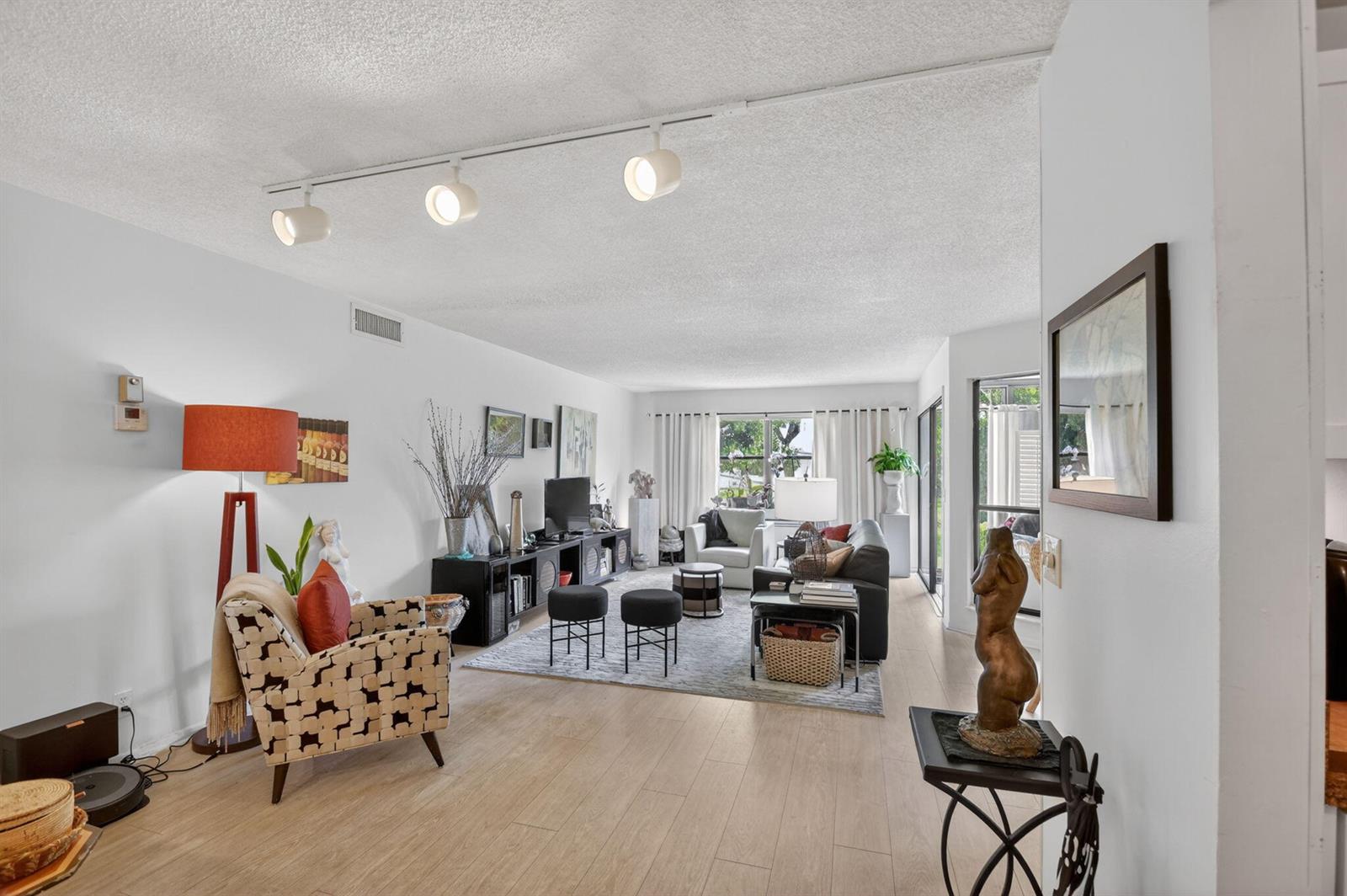 A living room with light wood floors, a track lighting system, and a patterned armchair — 3329 Perimeter Drive, FL 33467, FL