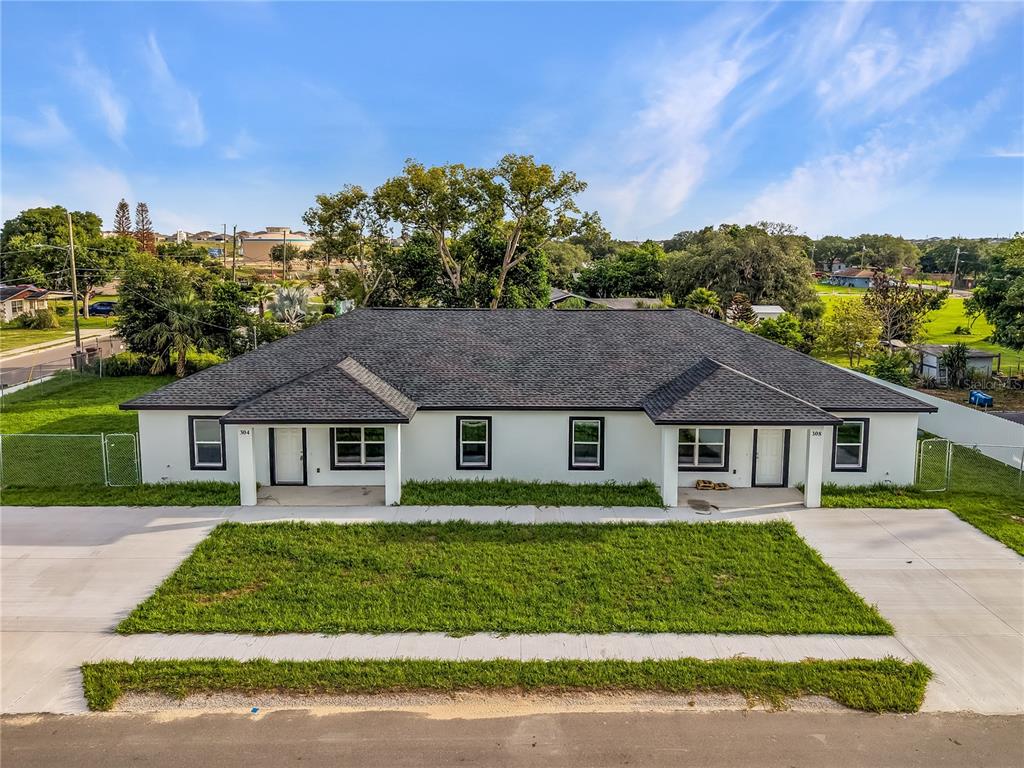 An exterior view of a single-story duplex with a dark shingled roof and white siding — 304 PEARL STREET, HAINES CITY, FL