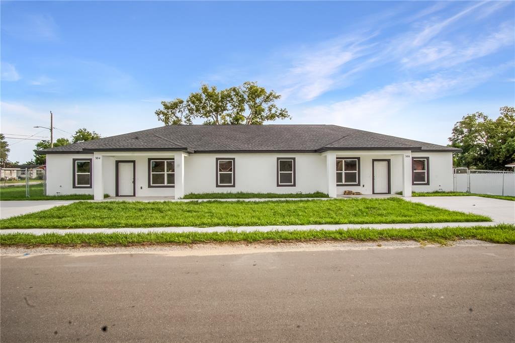 A single-story duplex with white exterior walls, dark trim, and a gray shingled roof — 304 PEARL STREET, HAINES CITY, FL