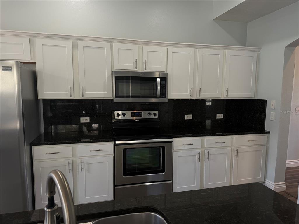 A bathroom features a double-sink vanity with a glass countertop and a large framed mirror — 109 GRACE AVENUE, KISSIMMEE, FL