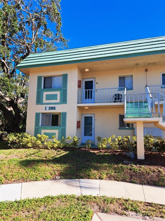 A two-story apartment building with beige stucco walls, teal shutters, and an exterior metal staircase — 2005 GREENBRIAR BOULEVARD UNIT 1, CLEARWATER, FL