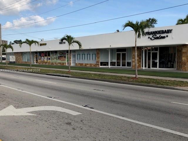 A single-story commercial strip mall features a row of storefronts and palm trees — MIAMI, FL