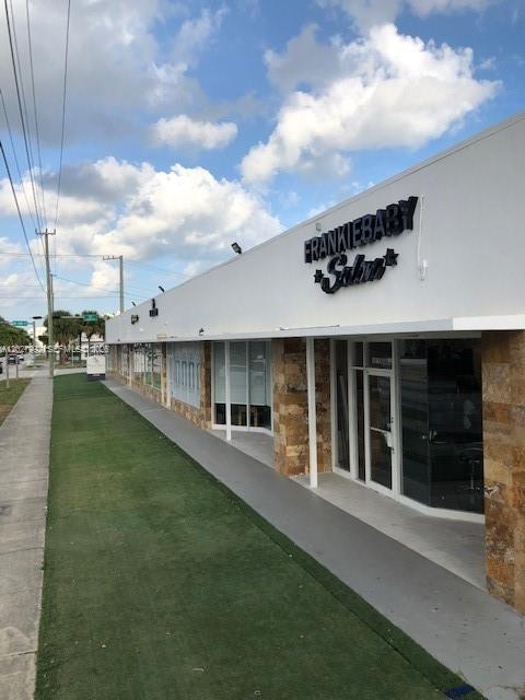 A view of a commercial building exterior with a salon sign and artificial grass walkway — MIAMI, FL
