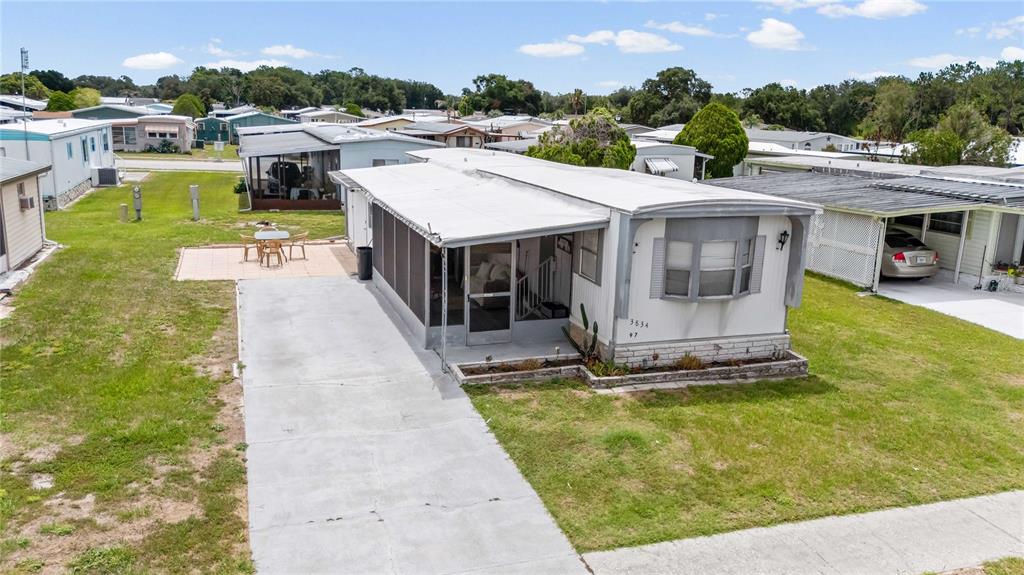 An exterior view of a manufactured home with a screened porch and concrete driveway — 3834 SARAH DRIVE, WESLEY CHAPEL, FL