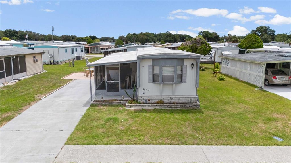 An exterior view of a single-wide mobile home with a screened porch and concrete driveway — 3834 SARAH DRIVE, WESLEY CHAPEL, FL