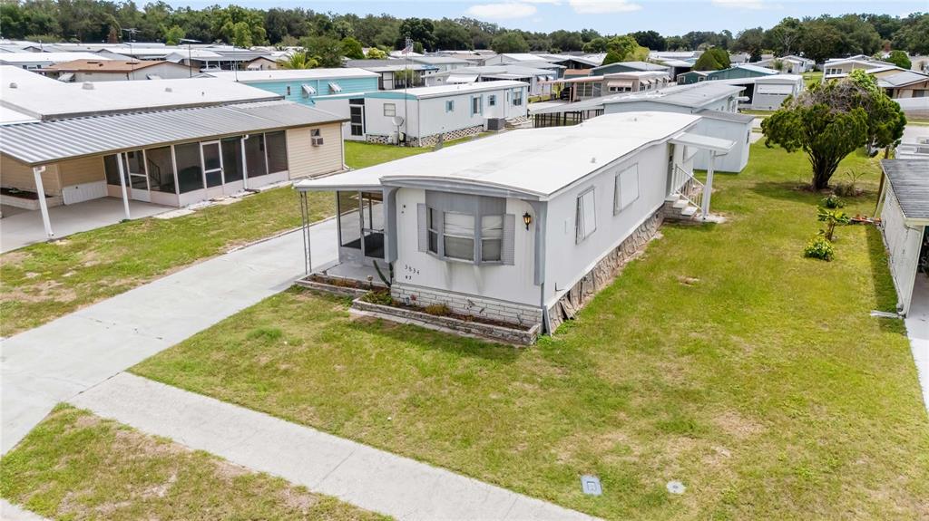 An elevated exterior view of a white mobile home with a screened porch and driveway — 3834 SARAH DRIVE, WESLEY CHAPEL, FL