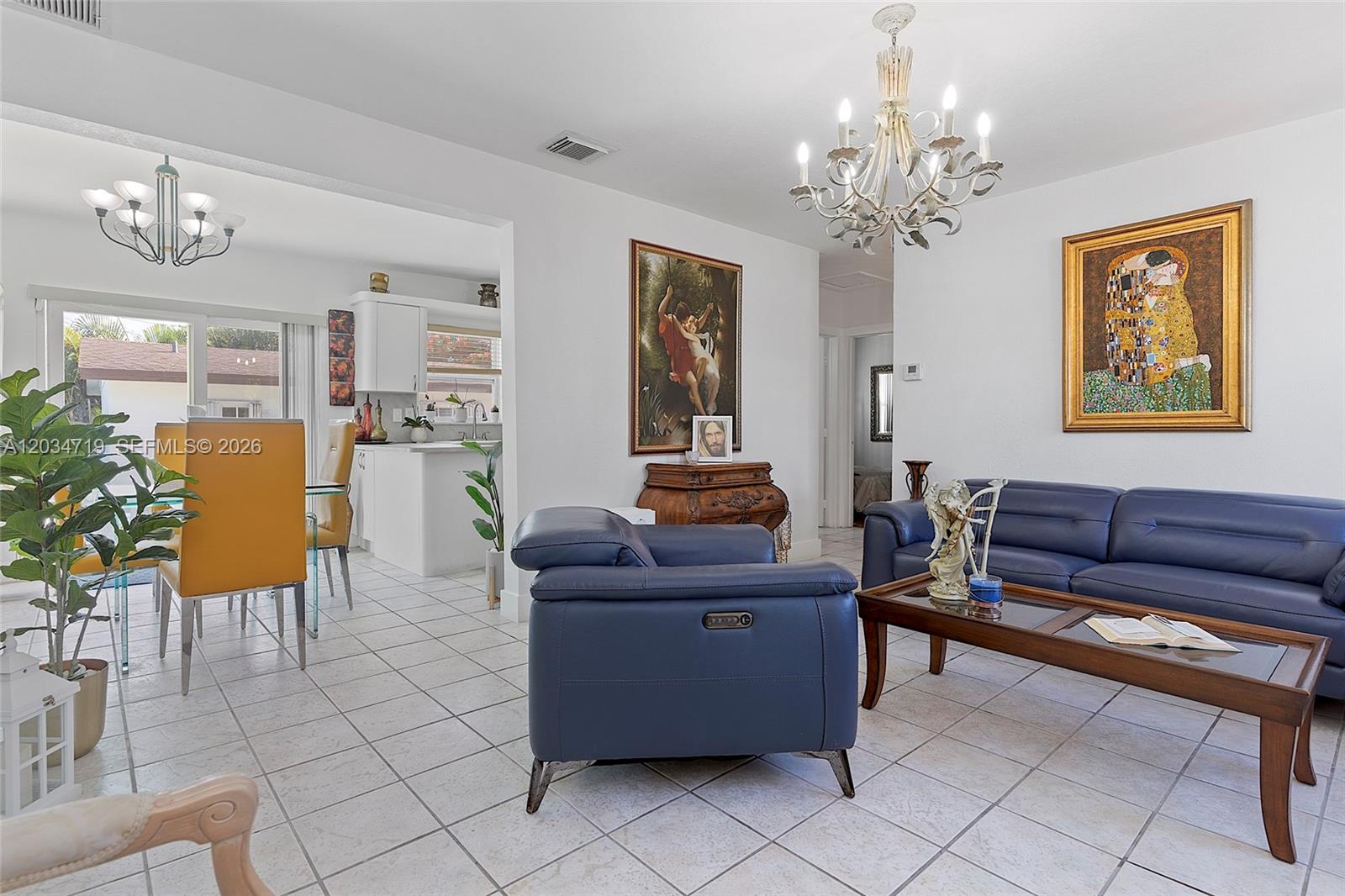 A living room with blue leather furniture, tile flooring, and a large chandelier — 6801 SW 27th St, Miami FL 33155, MIAMI, FL