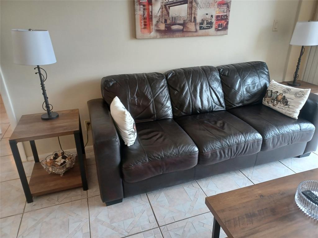 A living room features a dark leather sofa, two side tables with lamps, and wall art — 1391 S Ocean Boulevard # 105, Pompano Beach FL 33062, POMPANO BEACH, FL