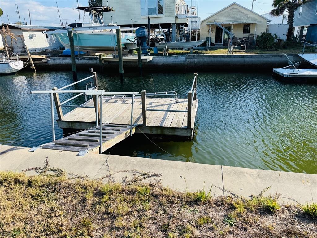 A wooden floating dock with a ramp sits in a canal near several boats — 6822 GULL LANE, HUDSON, FL