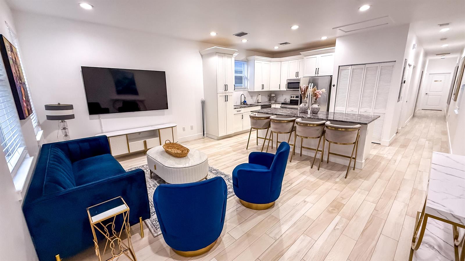 An open-concept living room and kitchen featuring blue velvet furniture and white cabinetry — 214 N C Street, FL 33460, FL