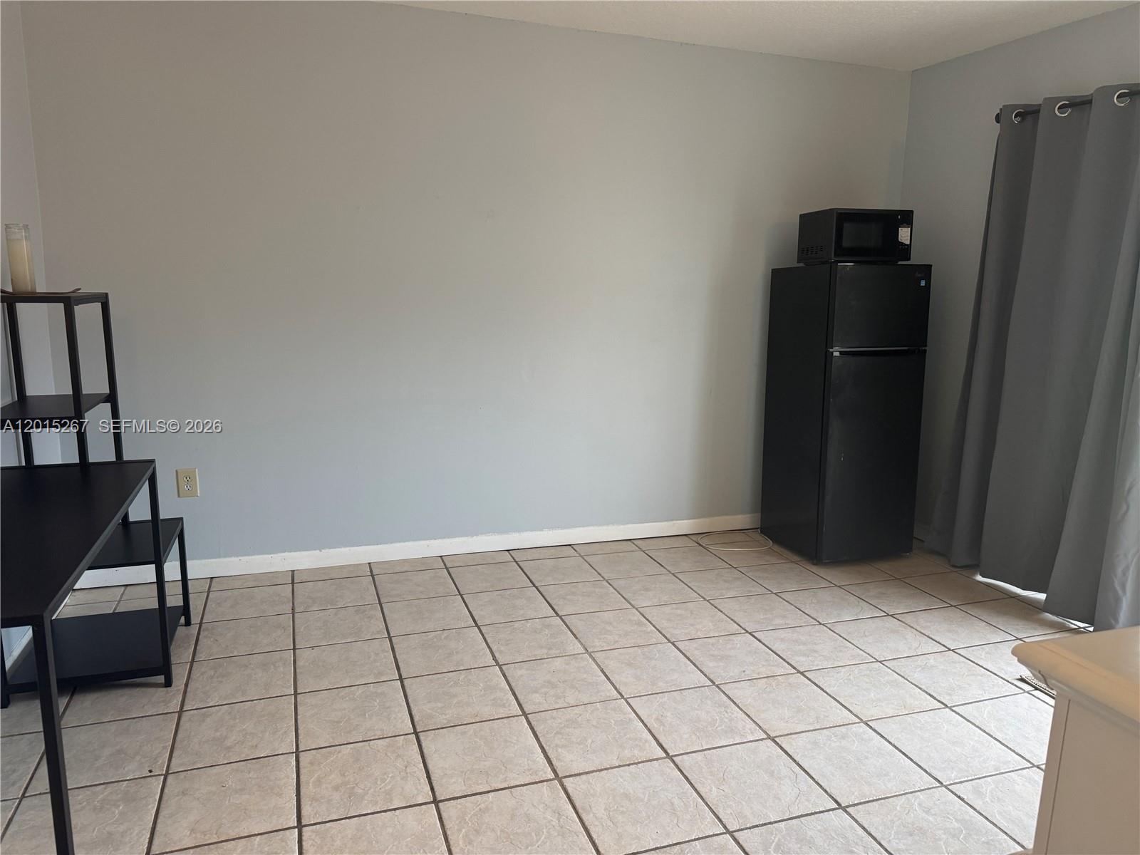 A room with light gray walls, tiled flooring, a black refrigerator, and a black shelf — 17016 SW 144th Ct # B, Miami FL 33177, MIAMI, FL