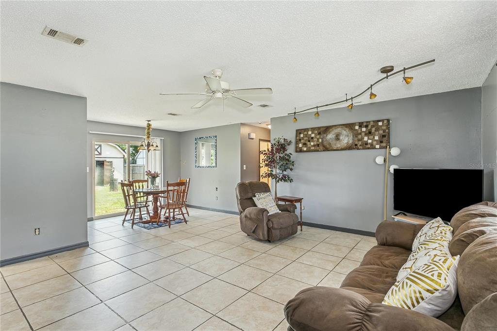 A living room and dining area with gray walls, tile flooring, and a ceiling fan — 10720 WILLOW LAKE DRIVE, PENSACOLA, FL