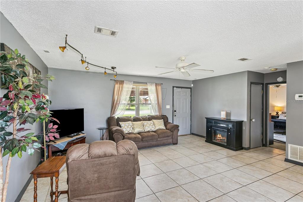 A living room features gray walls, tile flooring, a ceiling fan, and a fireplace — 10720 WILLOW LAKE DRIVE, PENSACOLA, FL
