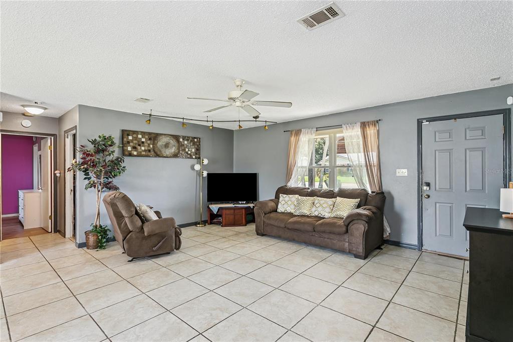 A living room with gray walls, tile flooring, a brown sofa, and a recliner — 10720 WILLOW LAKE DRIVE, PENSACOLA, FL