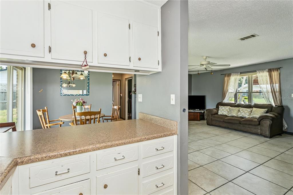 A kitchen counter overlooks a dining area and a living room with tile flooring — 10720 WILLOW LAKE DRIVE, PENSACOLA, FL