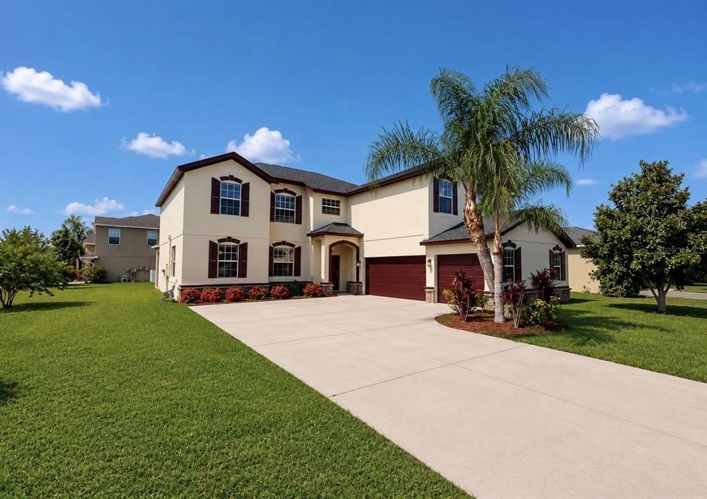 A two-story suburban house with a concrete driveway, a palm tree, and a garage — 125 ORANGE MILL AVENUE, RUSKIN, FL