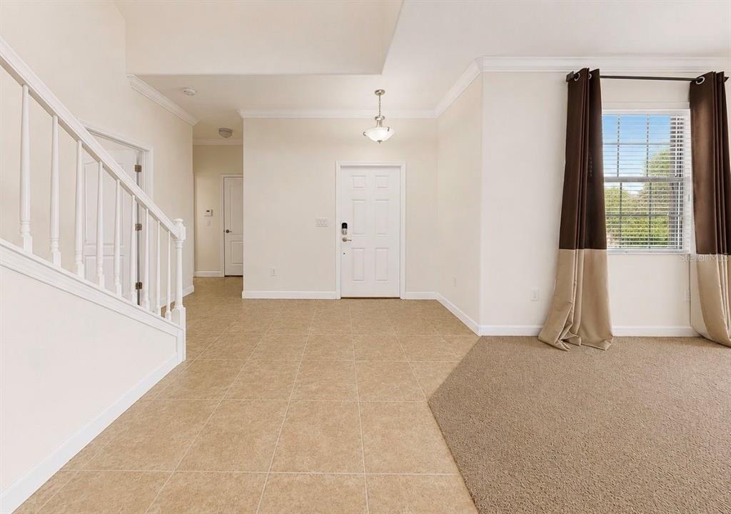 An entryway with tile flooring, a staircase, and a front door leads to a carpeted room — 125 ORANGE MILL AVENUE, RUSKIN, FL
