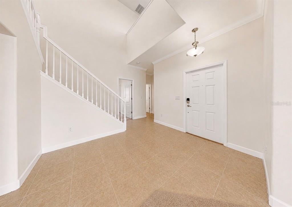 An entryway features a staircase with white railings, tile flooring, and a white front door — 125 ORANGE MILL AVENUE, RUSKIN, FL