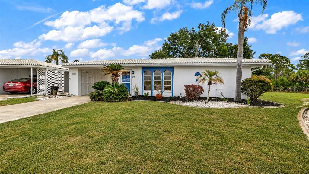 A white single-story house with a carport, a front lawn, and several palm trees — 546 CIRCLEWOOD DRIVE UNIT P3-4, VENICE, FL
