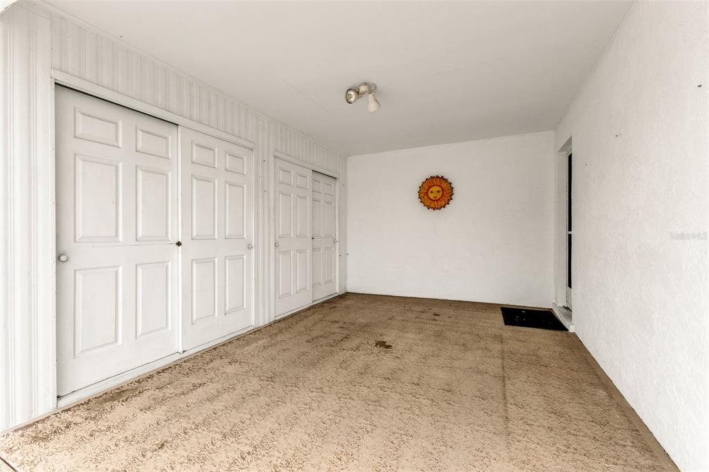 A covered patio features white walls, two sets of white double doors, and concrete flooring — 546 CIRCLEWOOD DRIVE UNIT P3-4, VENICE, FL