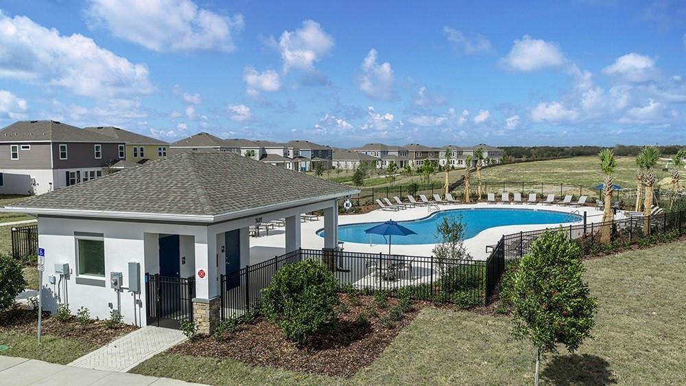 An outdoor swimming pool and a community building are surrounded by a black metal fence — 531 MOONSTONE COURT, GROVELAND, FL