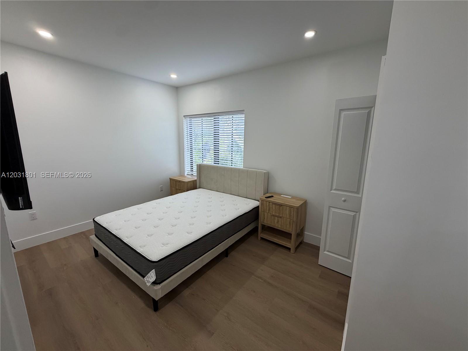 A bedroom features a bed with a mattress, two wooden nightstands, and light wood flooring — 1619 Jefferson Ave # 210, Miami Beach FL 33139, MIAMI BEACH, FL