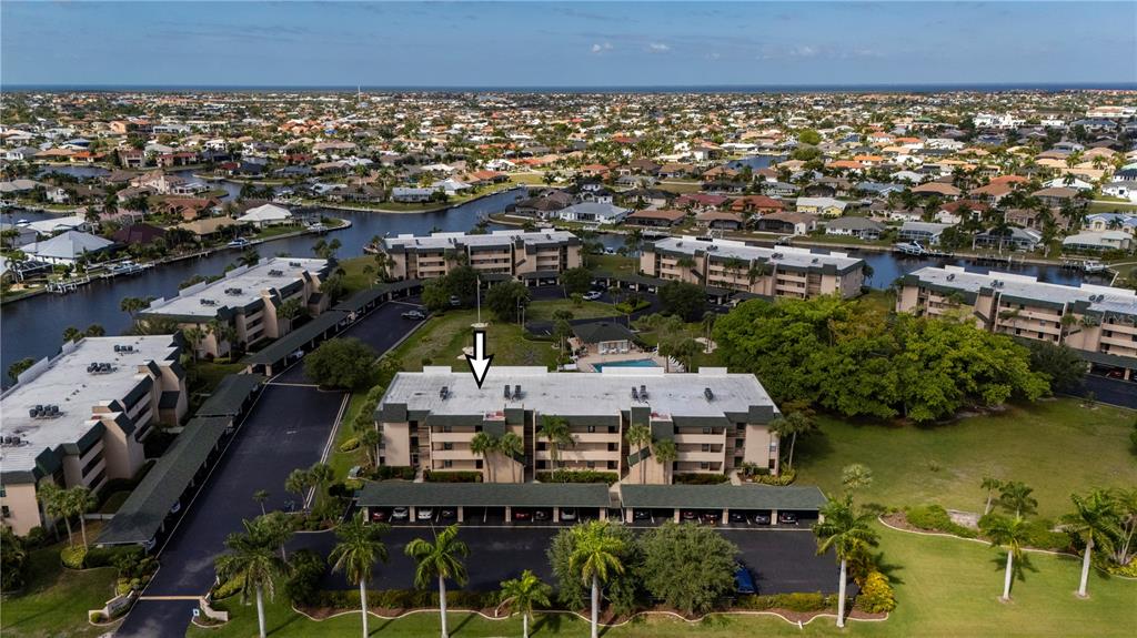 An aerial view shows a multi-story apartment complex with covered parking and surrounding landscaping — 601 SHREVE STREET UNIT 62C, PUNTA GORDA, FL
