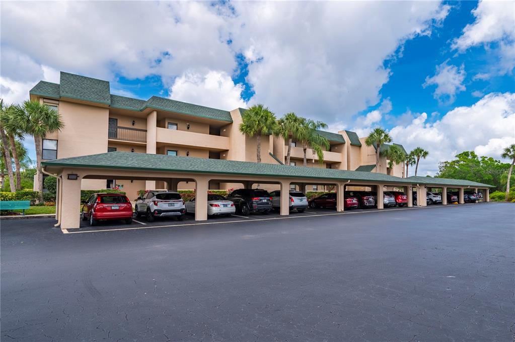 A multi-story apartment building with a long covered parking structure in the foreground — 601 SHREVE STREET UNIT 62C, PUNTA GORDA, FL