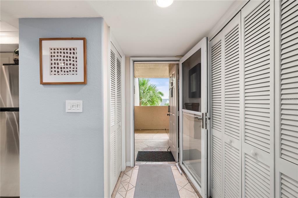 An entryway with a light blue wall, louvered closet doors, and an open door to a balcony — 601 SHREVE STREET UNIT 62C, PUNTA GORDA, FL
