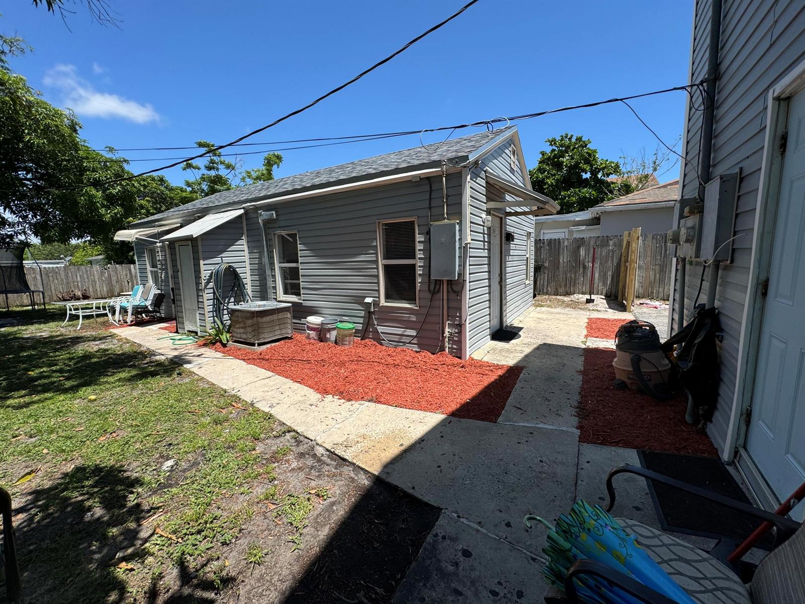 A gray-sided house exterior features a concrete walkway, red mulch, and an outdoor air conditioner — 717 S B Street # 715, FL 33460, FL