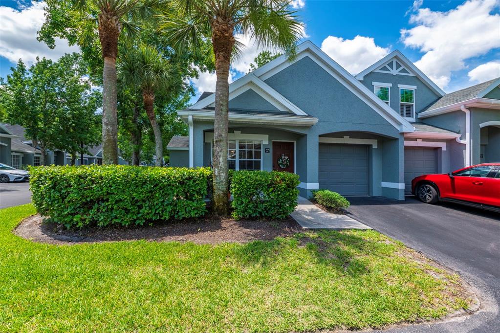 A blue-gray townhouse exterior features a single-car garage, a front door, and a manicured hedge — 3638 TRAFALGAR WAY UNIT 101, PALM HARBOR, FL