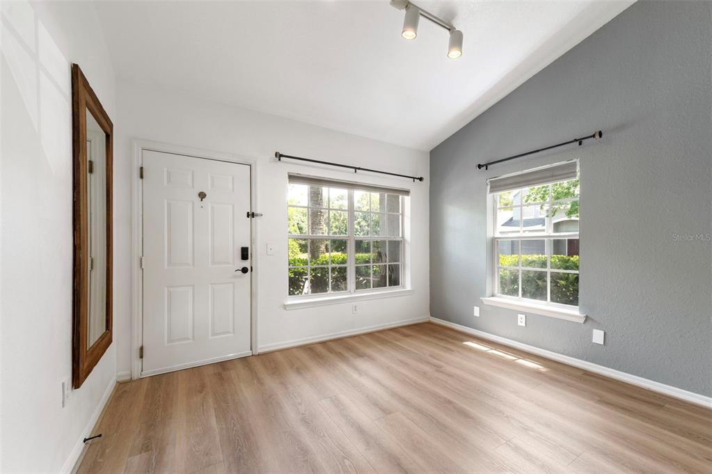 An empty room with light wood-look flooring, white walls, and a gray accent wall — 3638 TRAFALGAR WAY UNIT 101, PALM HARBOR, FL