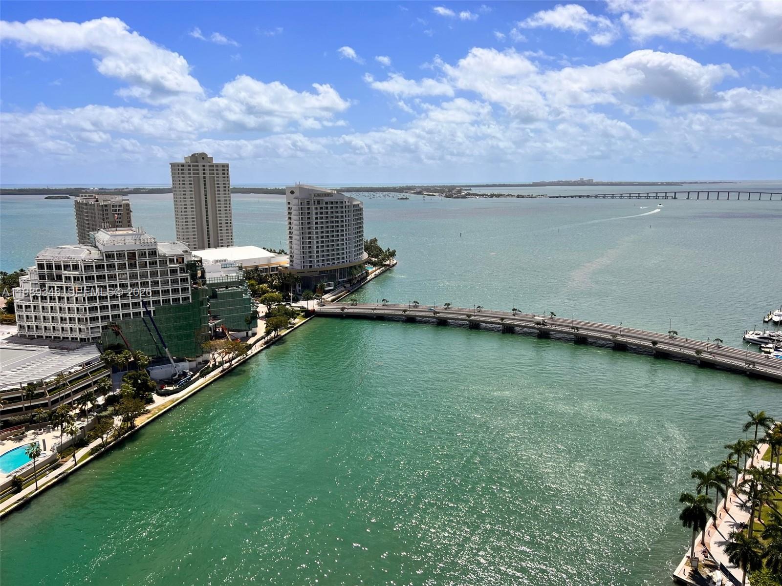 An aerial view shows high-rise buildings, a bridge over turquoise water, and a distant causeway — 495 Brickell Ave # 2401, Miami FL 33131, MIAMI, FL