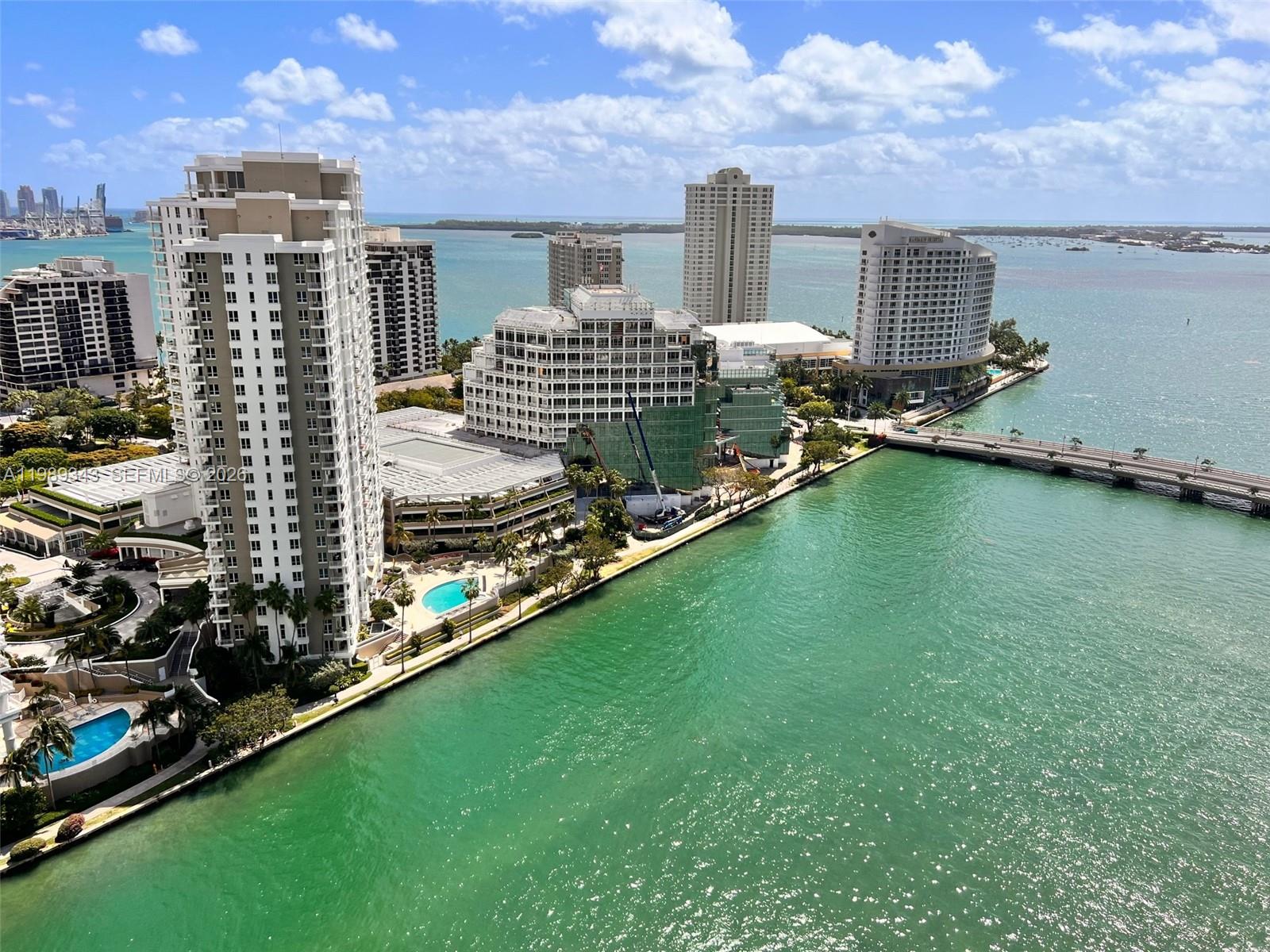 An aerial view shows high-rise buildings, a swimming pool, and a bridge over turquoise water — 495 Brickell Ave # 2401, Miami FL 33131, MIAMI, FL