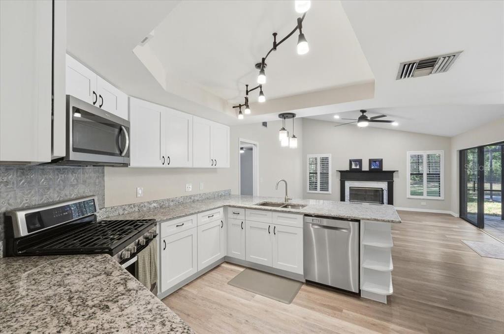A kitchen with white cabinets, granite countertops, stainless steel appliances, and an open floor plan — 2800 HAMMOCK DRIVE, PLANT CITY, FL