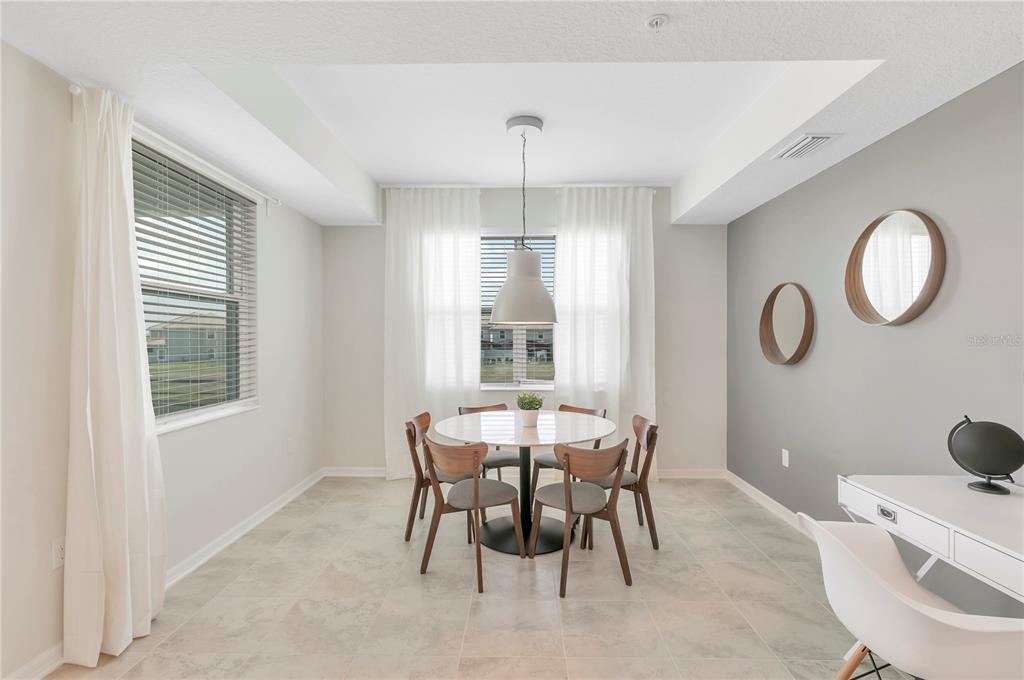 A dining area features a round table with four chairs, a pendant light, and tile flooring — 3121 PARADOX CIRCLE UNIT 203, KISSIMMEE, FL