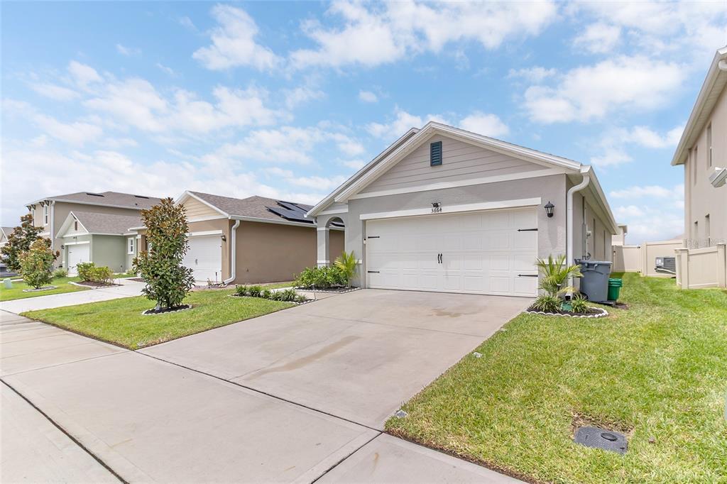A single-story suburban house with a gray exterior, white garage door, and a concrete driveway — 3664 SUNGROVE CIRCLE, SANFORD, FL