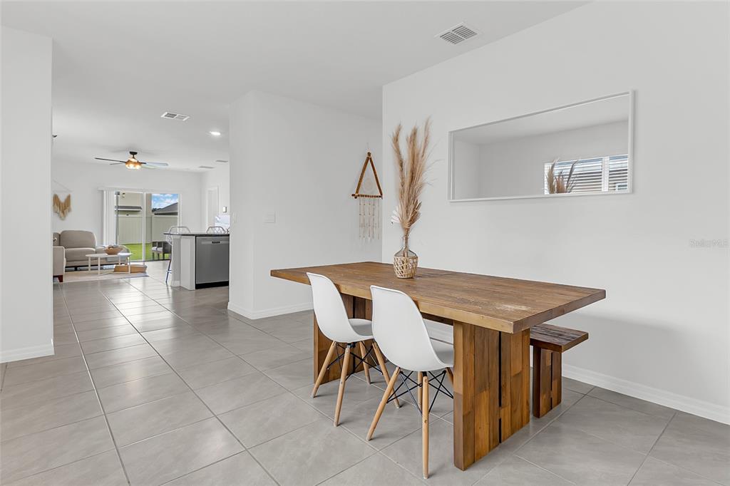 A dining area features a wooden table with white chairs and a bench on tile flooring — 3664 SUNGROVE CIRCLE, SANFORD, FL