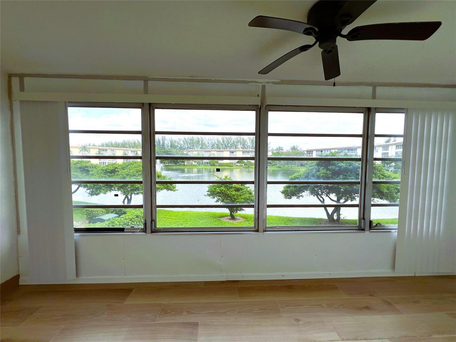 A room with light wood-look flooring and a large window overlooking a lake — 1902 Bermuda Circle # 2, Coconut Creek FL 33066, COCONUT CREEK, FL