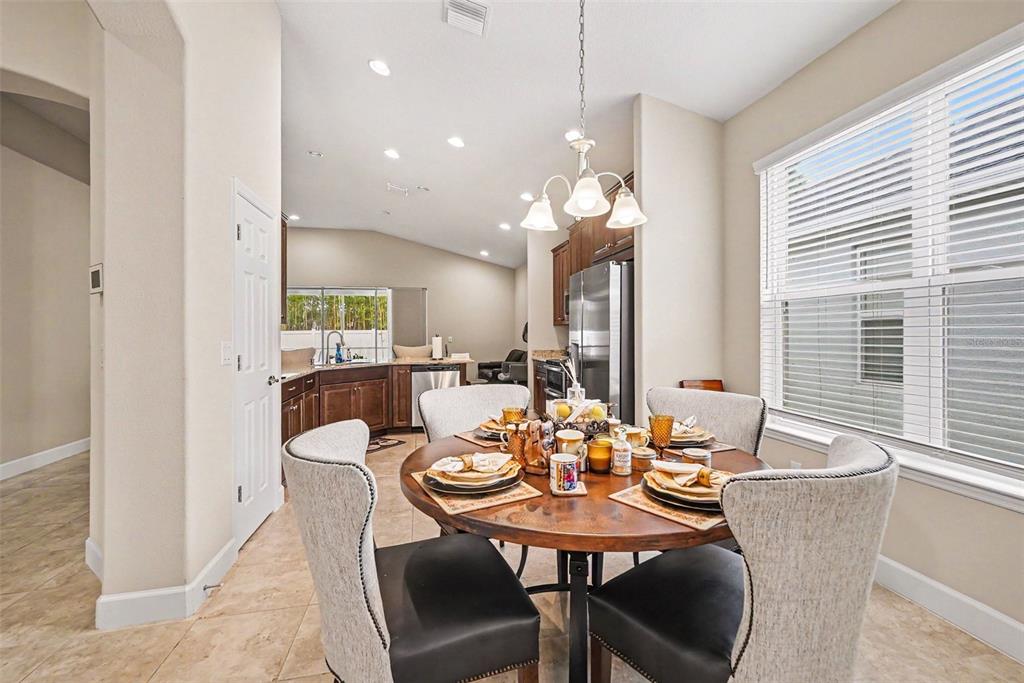 A dining area features a round wooden table, upholstered chairs, and an adjacent open kitchen — 7907 SILVER CLOVER COURT, RIVERVIEW, FL