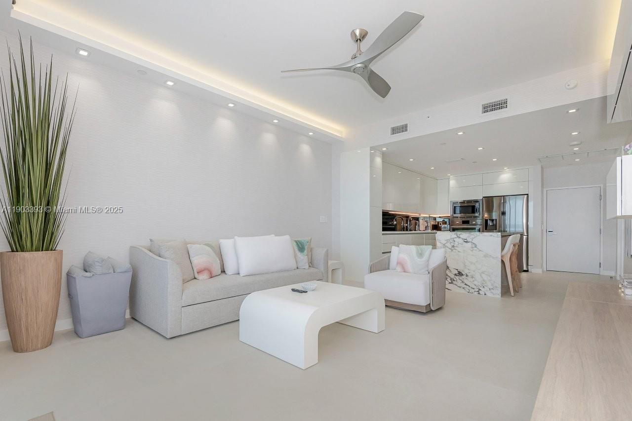 A modern living room features a white sofa, marble kitchen island, and recessed ceiling lighting — 2301 Collins Ave, Miami Beach FL 33139, MIAMI BEACH, FL