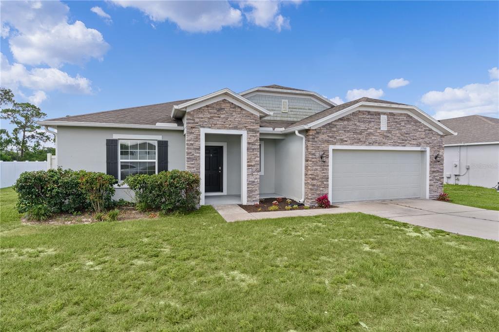 A single-story house with a stone facade, a two-car garage, and a front lawn — 15344 WHITE TAIL LOOP, MASCOTTE, FL