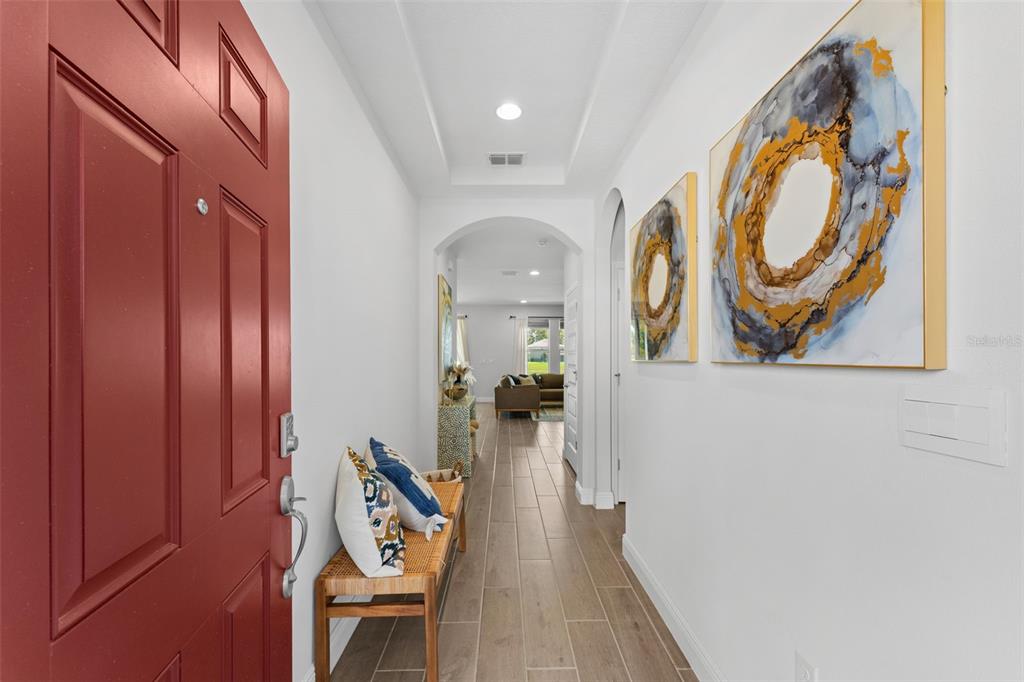 A bright entryway features a red front door, tiled floors, and abstract wall art — 8807 SONOMA COAST DRIVE, WINTER GARDEN, FL
