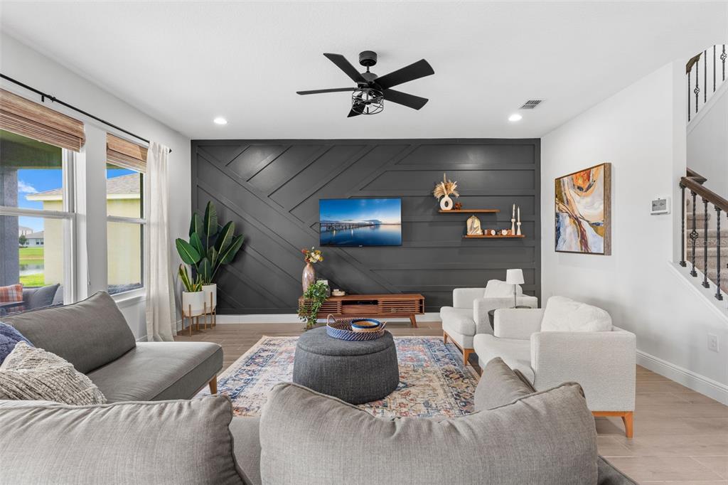 A living room features a dark gray accent wall with geometric trim and a television — 8807 SONOMA COAST DRIVE, WINTER GARDEN, FL