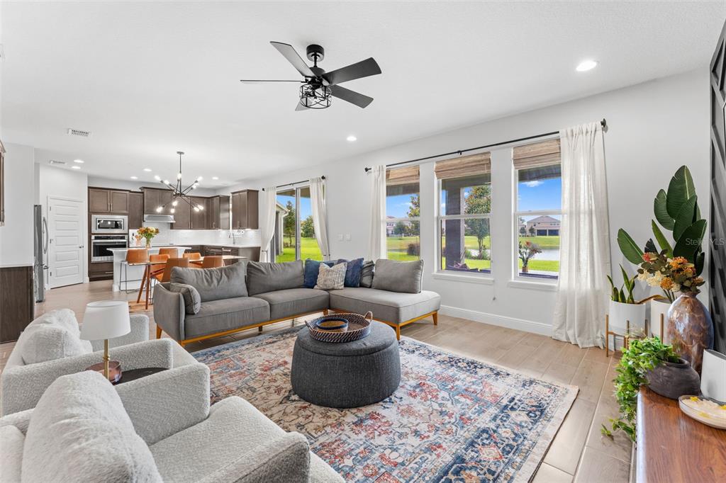 A living room with a gray sectional, round ottoman, and open kitchen in the background — 8807 SONOMA COAST DRIVE, WINTER GARDEN, FL