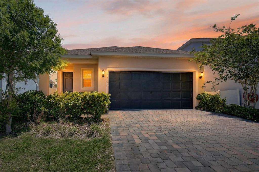 A single-story house with a dark garage door, a paved driveway, and a small front yard — 4406 DAVOS DRIVE, CLERMONT, FL